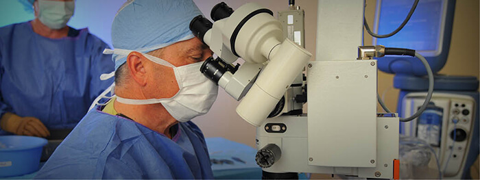 Ophthalmologist examining the retinas of a patient through a microscope.